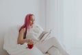 Beautiful woman with pink hair reading a book in a white room Royalty Free Stock Photo