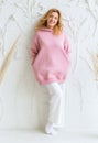 Beautiful woman in pink hoodie and white pants posing against white wall background Royalty Free Stock Photo