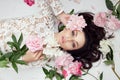 Beautiful woman with pink peony flowers, natural beauty, skin care. Perfect facial features. Girl posing on a light background Royalty Free Stock Photo