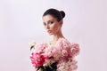 Beautiful woman with pink peony flowers, natural beauty, skin care. Perfect facial features. Girl posing on a light background Royalty Free Stock Photo