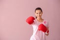 Beautiful woman with pink ribbon and boxing gloves on color background. Breast cancer concept Royalty Free Stock Photo