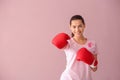 Beautiful woman with pink ribbon and boxing gloves on color background. Breast cancer concept