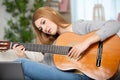 beautiful woman playing acoustic guitar on sofa at home Royalty Free Stock Photo
