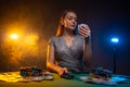 Beautiful woman playing in casino and look at her cards. Lucky player on smoky background with lamps. Concept of poker game