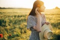 Beautiful woman with poppy flower behind ear relaxing in barley field in sunset light. Stylish female standing in evening summer Royalty Free Stock Photo