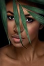 Beautiful woman portrait on black background. Young afro girl posing with green leaves and closed eyes. Gorgeous make up. Royalty Free Stock Photo