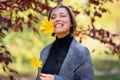 Beautiful woman portrait, she put the maple leaf in her mouth and is surprised, smile broadly, posing in autumn city park, bright Royalty Free Stock Photo