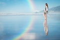 Beautiful woman posing at amazing beach with rainbow in the sky