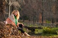 Beautiful woman posing in park during autumn season. Blonde girl wearing green blouse and big shawl posing outdoor. Long fair hair Royalty Free Stock Photo