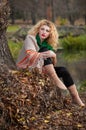 Beautiful woman posing in park during autumn season. Blonde girl wearing green blouse and big shawl posing outdoor. Long fair hair Royalty Free Stock Photo
