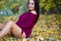 Beautiful woman posing sitting ground in autumn park