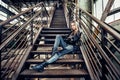 Beautiful woman posing wearing casual outfit with leather jacket, black shoes and fashionable jeans. Girl posing in industrial pla Royalty Free Stock Photo