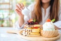 A woman pouring honey into a piece of mixed berries pancakes with ice cream and whipped cream Royalty Free Stock Photo