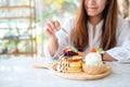 A woman pouring honey into a piece of mixed berries pancakes with ice cream and whipped cream Royalty Free Stock Photo