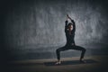 Beautiful woman practices yoga asana Stupasana in the dark hall Royalty Free Stock Photo