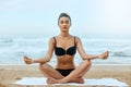 Beautiful woman practices yoga and meditates in the lotus position on th ebeach