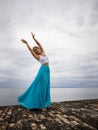 Beautiful woman practicing ballet pose. Young ballerina wearing long blue skirt and dancing. Outdoor ballet practice. Slim body. Royalty Free Stock Photo