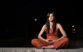 Beautiful woman practicing meditation at night