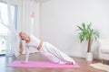 Beautiful woman is practicing yoga at home on yoga mat, girl doing Camatkarasana pose