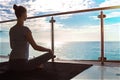 The beautiful woman practicing yoga on a rug and sitting on a balcony with the seaside view.