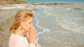 Beautiful woman prays on the sea shore