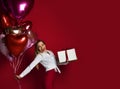 Beautiful woman with present gift box and purple pink heart balloons happy smiling on red background Royalty Free Stock Photo