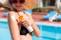 Beautiful woman protecting her skin against sunburn, applying sun lotion on her shoulder by the pool. Sun Protection Factor in Royalty Free Stock Photo