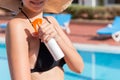 Beautiful woman protecting her skin against sunburn, applying sun lotion on her shoulder by the pool. Sun Protection Factor in Royalty Free Stock Photo