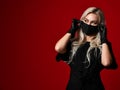 Beautiful woman in protective black medical mask and gloves on dark red background