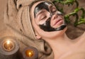 Beautiful woman with purifying black mask on her face. Beauty model girl with black facial peel-off mask lying in spa salon Royalty Free Stock Photo