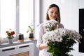 Beautiful woman putting fresh white flowers into a vase Royalty Free Stock Photo