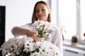 Beautiful woman putting fresh white flowers into a vase Royalty Free Stock Photo