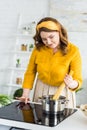 beautiful woman putting pasta into pan with water