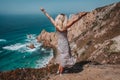 Beautiful women raising hands enjoying impressive Praia da Ursa Beach. Surreal scenery of Sintra, Portugal. Atlantic