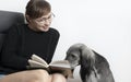 Beautiful woman reading book with her dog. greyhound sduty read