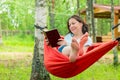 Beautiful woman reading a book sitting in a red hammock in the g Royalty Free Stock Photo