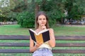 Beautiful woman is reading a book and thinking about something on the bench in the park. Girl has some thoughts and ideas Royalty Free Stock Photo