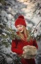 Beautiful woman in red with brown fur cape enjoying the winter scenery in forest. Blonde girl posing under snow-covered trees Royalty Free Stock Photo