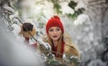 Beautiful woman in red with brown fur cape enjoying the winter scenery in forest. Blonde girl posing under snow-covered trees Royalty Free Stock Photo