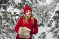 Beautiful woman in red with brown fur cape enjoying the winter scenery in forest. Blonde girl posing under snow-covered trees Royalty Free Stock Photo