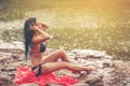 Beautiful women in red cloth happy sitting playing a water along the riverside. Young women enjoy playing water alone outdoor Royalty Free Stock Photo