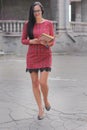 Beautiful woman in a red dress, with a book in her hands goes forward near the institute