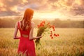 Beautiful woman in a red dress with a bouquet of poppies in a wheat field at sunset, warm toning, happiness and a healthy lifestyl Royalty Free Stock Photo