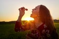 Beautiful woman in red dress holding basket and eating strawberry. Female model posing with red berry on the green field during Royalty Free Stock Photo