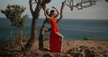 Beautiful woman in red dress on the sea shore cliff during over sea and sky background Royalty Free Stock Photo