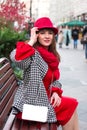 A beautiful woman in a red dress is sitting on a bench, looking out. Royalty Free Stock Photo