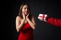 Beautiful woman in red evening gown receiving a gift box guessing with closed eyes Royalty Free Stock Photo