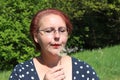 beautiful woman with red hair blows into dandelion outdoors Royalty Free Stock Photo