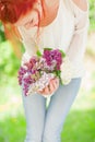 Beautiful woman with red hair holding white and violet lilac bloom in her hands, outdoor garden Royalty Free Stock Photo