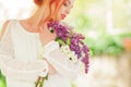 Beautiful woman with red hair holding white and violet lilac bloom in her hands, outdoor garden Royalty Free Stock Photo